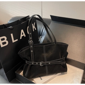 Détail du cabas en cuir noir mat avec surpiqûres blanches et sangle à boucle en métal