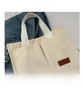 Detail view of corduroy tote bag featuring front dual pockets and fashion leather label