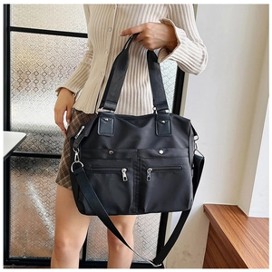 Détail du sac en nylon noir avec rivets métalliques et poignées en cuir renforcées