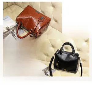Détail de sacs vintage à rivets et poignées posés sur un canapé en cuir beige
