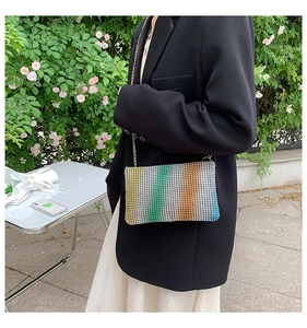 Detail of colorful rainbow rhinestone crossbody bag with gold chain strap on a model