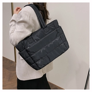 Side view of a black quilted nylon tote bag worn on shoulder for commuting style