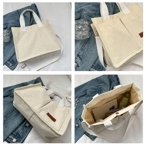 Detail view of beige corduroy tote bag showing front pockets and brown fashion leather tag