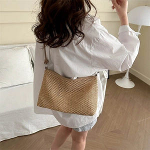 Sac à bandoulière chic en paille tissée pour la plage présenté dans un décor élégant
