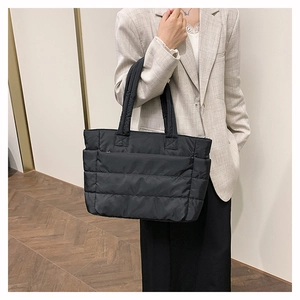 Detail of black quilted nylon tote bag showing lightweight fabric and side pockets