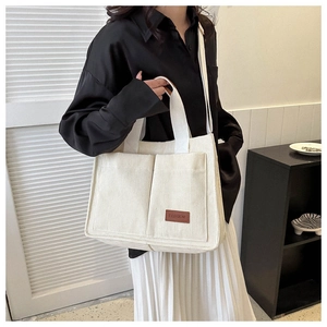 Detail of off-white corduroy tote bag showing front double pockets and fashion label