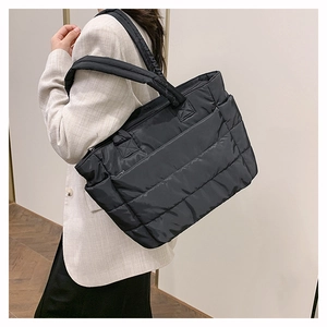 Black quilted puffer tote bag shown on shoulder to illustrate large capacity and size