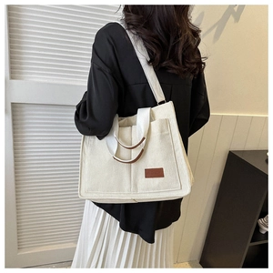 Detail of white corduroy tote bag showing the fashion label and soft ribbed texture