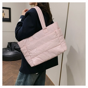 Detailed side view of a large pink quilted nylon tote bag worn with a navy blazer