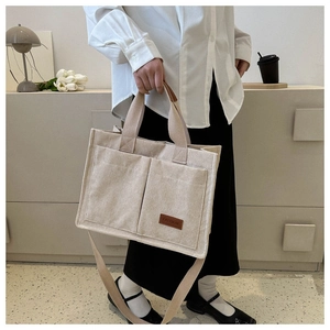 Detail of corduroy tote bag featuring front pockets and adjustable shoulder strap