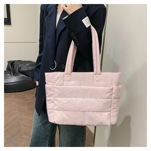 Close-up of pink quilted nylon tote bag worn with a navy suit for a stylish contrast