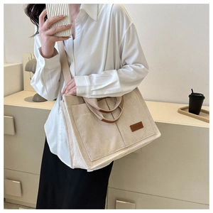 Detail of beige corduroy tote bag showing front pockets and leather fashion label