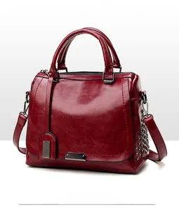Détail d'un sac cabas en cuir huilé bordeaux vintage avec rivets et bandoulière réglable