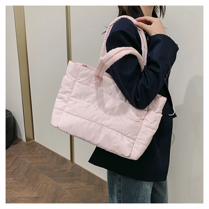 Pink quilted nylon tote bag worn by a model in a modern interior, side view of the fluffy bag