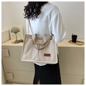 Detail of off-white corduroy tote bag showing large front pockets and FASHION leather tag