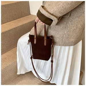 Detail of suede mini crossbody bag with leather knot handles and adjustable shoulder strap