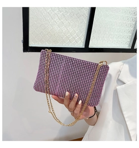 Detail of a luxury evening bag with purple rhinestones and a gold metal chain strap