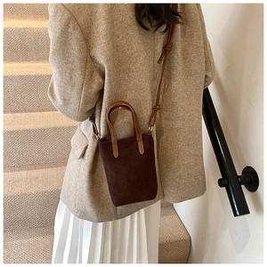 Detail of dark brown suede mini crossbody bag worn with elegant beige blazer outfit
