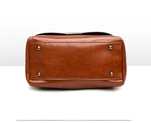 Détail du fond du sac avec quatre rivets métalliques protecteurs et texture en cuir huilé