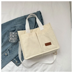 Detailed view of beige corduroy tote bag showing front pockets and fashion patch logo