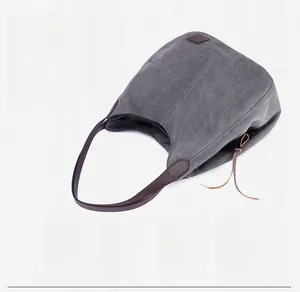Close-up of gray canvas tote bag featuring premium leather handles and a leaf logo