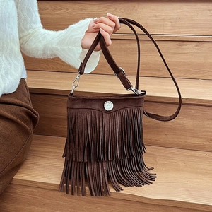 Close-up of brown fringe bucket bag with silver metal buckle on a wooden background