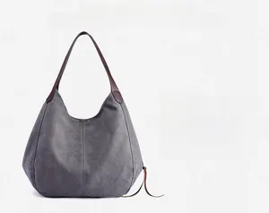 Detail of grey washed canvas tote bag with brown leather handles and vertical stitching