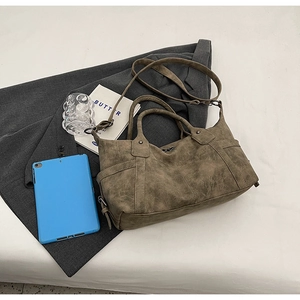 Flat lay of vintage taupe tote bag with double handles and long strap on office desk