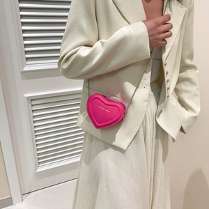 Détail d'un mini sac bandoulière en forme de cœur rose avec chaîne argentée