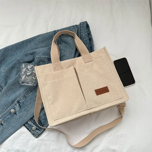 Minimalist beige corduroy tote bag with large front pockets and adjustable shoulder strap
