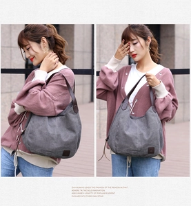 Detailed view of grey canvas tote bag featuring premium brown leather handles and logo