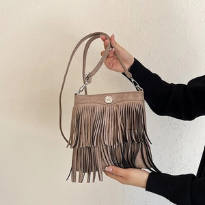 Detail view of brown suede bucket bag featuring long fringe tassels and metal logo