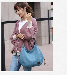 Outdoor shot of a blue canvas tote bag with brown leather handles and fringe zipper detail