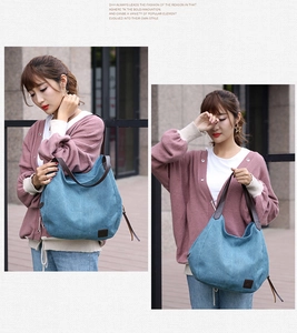 Detail view of blue canvas hobo tote bag with brown leather brand tag and straps