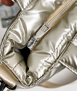 Detail van zilveren puffy tote met gladde metalen rits en glanzende gewatteerde textuur