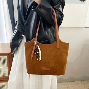 Deep brown suede tote bag with wooden bead charm worn with black leather blazer