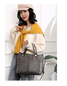 Detailansicht einer grauen Vintage-Tragetasche mit zwei Fronttaschen und Silbernieten