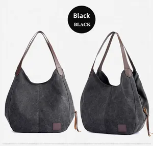 Detail view of large black canvas tote bag with brown leather accents and side drawstring