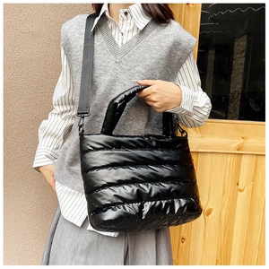 Detail van zwarte gewatteerde shopper met glanzende afwerking en afneembare schouderriem