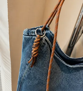 Detail of high-gloss silver metal rings and dual-tone braided rope on denim tote bag