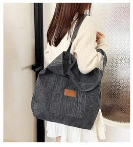 Détail du grand sac cabas en denim gris avec étiquette en cuir porté par un mannequin