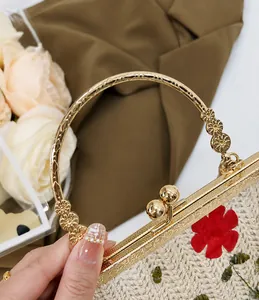 Détail de la poignée florale dorée et broderie vintage sur sac de soirée en paille