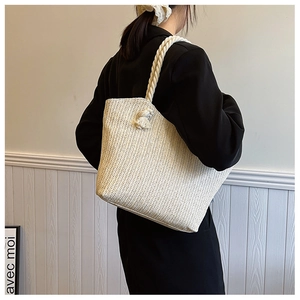 Vue détaillée du sac cabas en paille tressée crème avec anses en corde de coton et des glands