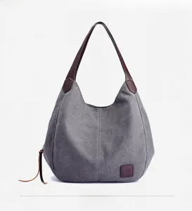 Front view of grey canvas tote bag with brown leather handles and minimalist details