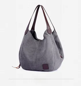 Detailed side view of grey canvas tote bag with brown leather handles and textured surface