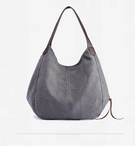 Detail view of dark grey canvas tote back side with brown leather handles and strap