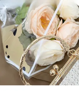 Detail of woven beige handbag featuring gold round carved handle and spherical metal clasp