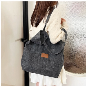 Détail du sac cabas en toile gris foncé avec écusson en cuir marron et large bandoulière