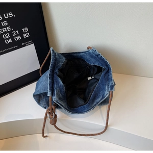 Detail view showing large denim tote interior with black lining and woven rope strap
