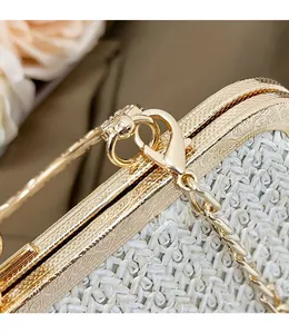 Detailed shot of removable gold metal chain buckle on woven straw shoulder bag